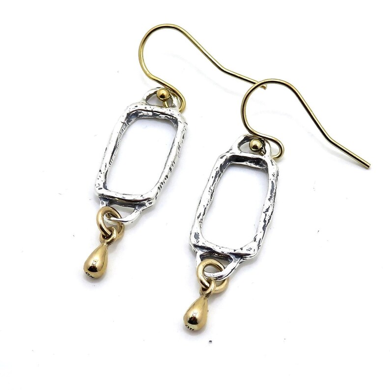 Op de afbeelding: Zilveren en gouden oorhangers met een rechthoekige vorm en een traanvormige hanger.