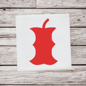 May include: A red apple core graphic on a white square. The apple core is a solid red color and is centered on the square. The background is a wooden surface.