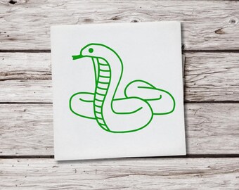 May include: A green line drawing of a snake on a white square. The snake is coiled with its head raised, tongue extended. The artwork is set against a light wood-grain background.