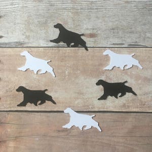 May include: Six paper cutouts of a running dog, three are black and three are white. The cutouts are arranged in a circle on a woodgrain surface.