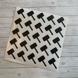 May include: A sheet of white stickers featuring a repeating pattern of black hammer shapes. The stickers are arranged in neat rows and columns, creating a grid-like design. The hammers have a rectangular head and a long, thin handle.