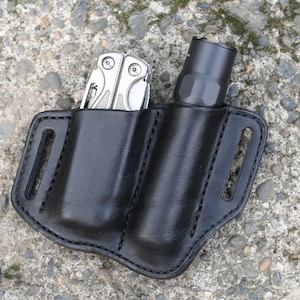 May include: A black leather belt holster with two pockets, one for a multi-tool and one for a flashlight.