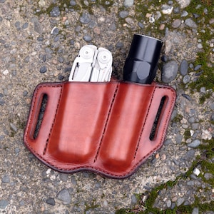 Puede incluir: Una funda de cuero marrón de doble bolsillo con una multiherramienta y una linterna en su interior.