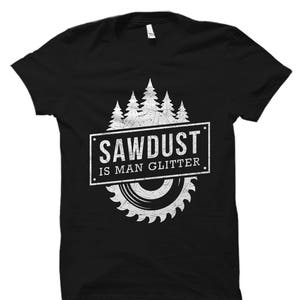 May include: Black t-shirt with a white graphic design featuring a saw blade and trees. The text "Sawdust is Man Glitter" is printed on the shirt.