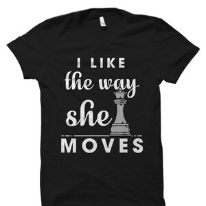 May include: Black t-shirt with the text "I like the way she moves" and a white chess queen graphic.