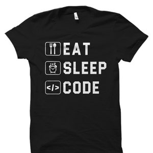 May include: Black t-shirt with white text that reads "Eat Sleep Code" with icons of a fork and knife, a clock with a sleeping face, and angle brackets.