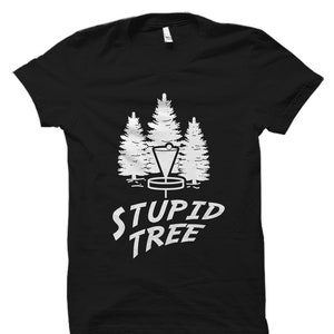 May include: Black t-shirt with a white graphic of three trees and a disc golf basket. The text "STUPID TREE" is printed below the graphic.
