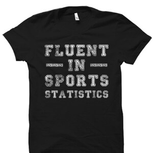 May include: Black t-shirt with white text that reads "Fluent in Sports Statistics".
