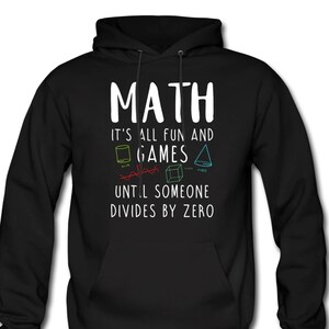 以下が含まれることがあります： 黒いフード付きスウェットシャツに、白い文字で「MATH IT'S ALL FUN AND GAMES UNTIL SOMEONE DIVIDES BY ZERO」と書いてあります。テキストはカラフルな幾何学模様で囲まれています。