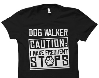 May include: Black t-shirt with white text that reads "Dog Walker Caution: I Make Frequent Stops" with a paw print in the word "Stops".