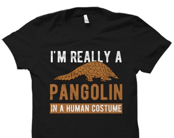 May include: Black t-shirt with the text "I'm really a pangolin in a human costume" in white and brown text. A cartoon pangolin is illustrated above the text.