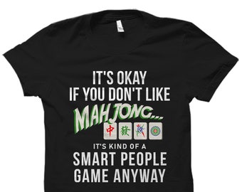 May include: Black t-shirt with white text that reads "It's okay if you don't like Mahjong... It's kind of a smart people game anyway". The text is surrounded by four mahjong tiles.