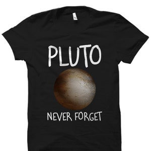 Puede incluir: Camiseta negra con texto blanco que dice "PLUTO NEVER FORGET" y una imagen marrón de Plutón.