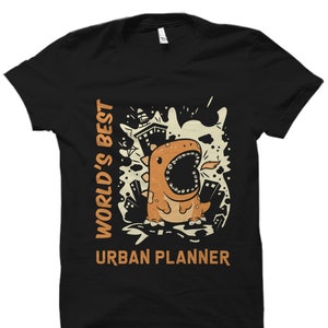 May include: Black t-shirt with a cartoon dinosaur and the text "World's Best Urban Planner".