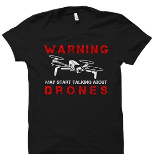 May include: Black t-shirt with a white drone graphic and red text that reads "WARNING MAY START TALKING ABOUT DRONES".