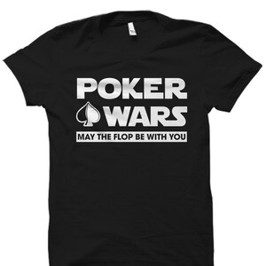 May include: Black t-shirt with white text that reads "Poker Wars" with a spade symbol and the phrase "May the flop be with you".
