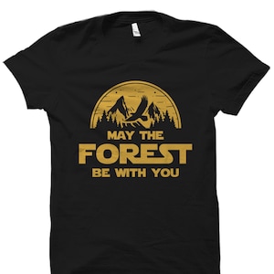 May include: Black t-shirt with a gold graphic of a mountain range, a flying eagle, and the text "May the Forest Be With You".