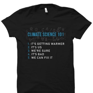Puede incluir: Camiseta negra con un gráfico azul que dice "Climate Science 101" y enumera cinco puntos: "Se está calentando", "Somos nosotros", "Estamos seguros", "Es malo", y "Podemos arreglarlo".