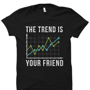 Op de afbeelding: Zwart T-shirt met een witte afbeelding van een lijndiagram met de tekst "The Trend Is Your Friend".
