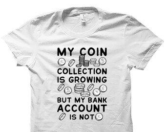 Könnte beinhalten: Weißes T-Shirt mit schwarzem Text: "MY COIN COLLECTION IS GROWING BUT MY BANK ACCOUNT IS NOT". Das Design zeigt Münz-Illustrationen. Rundhalsausschnitt, kurze Ärmel. Für Münzsammler.
