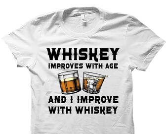 May include: White t-shirt with a black graphic that says "Whiskey improves with age and I improve with whiskey". The graphic also includes two illustrations of glasses of whiskey.