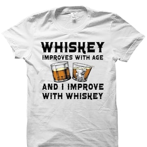 May include: White t-shirt with a black graphic that says "Whiskey improves with age and I improve with whiskey". The graphic also includes two illustrations of glasses of whiskey.