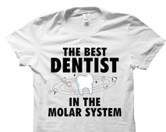 May include: White t-shirt with black text that reads "The Best Dentist in the Molar System". A cartoon tooth is in the center of the text, surrounded by smaller teeth.