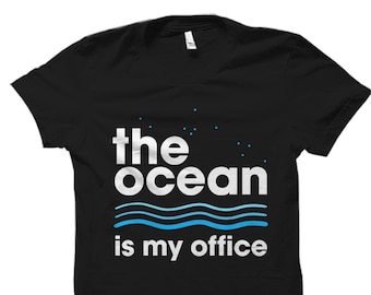 May include: Black t-shirt with white text that reads "the ocean is my office". The text is surrounded by blue wavy lines.