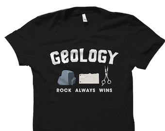 Könnte beinhalten: Schwarzes T-Shirt mit weißem Text, der "Geology Rock Always Wins" lautet. Das Shirt zeigt eine kleine Illustration eines Steins, eines Papierstücks und einer Schere.