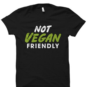 May include: Black t-shirt with white text that reads "Not Vegan Friendly" in a green font.