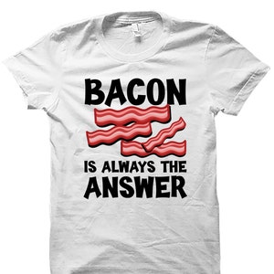 May include: White t-shirt with the text "BACON IS ALWAYS THE ANSWER" in black. The text is surrounded by a graphic of four strips of bacon.