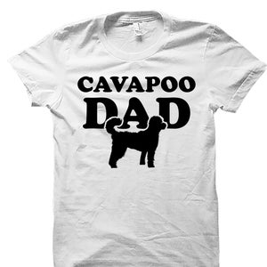 May include: White t-shirt with black text that reads "Cavapoo Dad" and a black silhouette of a Cavapoo dog.