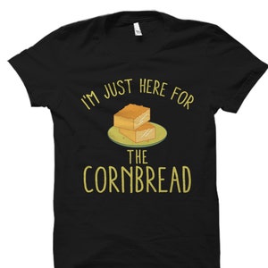May include: Black t-shirt with the text "I'M JUST HERE FOR THE CORNBREAD" in yellow. The graphic features two square pieces of cornbread on a green plate.