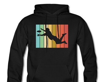 May include: Black hoodie featuring a vintage-style graphic of a person playing frisbee. The graphic is set against a colourful striped background.