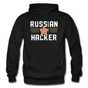 Könnte beinhalten: Schwarzer Kapuzenpullover mit dem Text "RUSSIAN HACKER" in weißen Buchstaben. Ein roter Stern mit Hammer und Sichel darin befindet sich über dem Text.