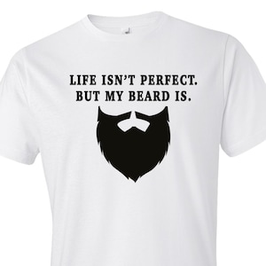 May include: White t-shirt with black text that reads "Life isn't perfect. But my beard is." and a black silhouette of a beard.