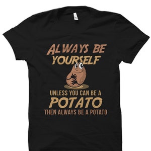 May include: Black t-shirt with a white graphic of a potato with a face and the text "Always be yourself unless you can be a potato then always be a potato."