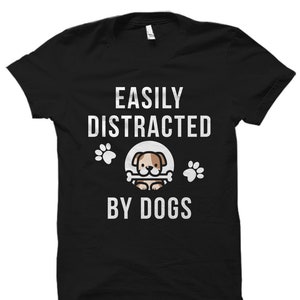 May include: Black t-shirt with white text that reads "Easily Distracted By Dogs". A cartoon dog with a bone is in the center of the text.