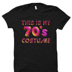 Puede incluir: Camiseta negra con el texto "This is my 70's Costume" en letras con degradado rosa y naranja.