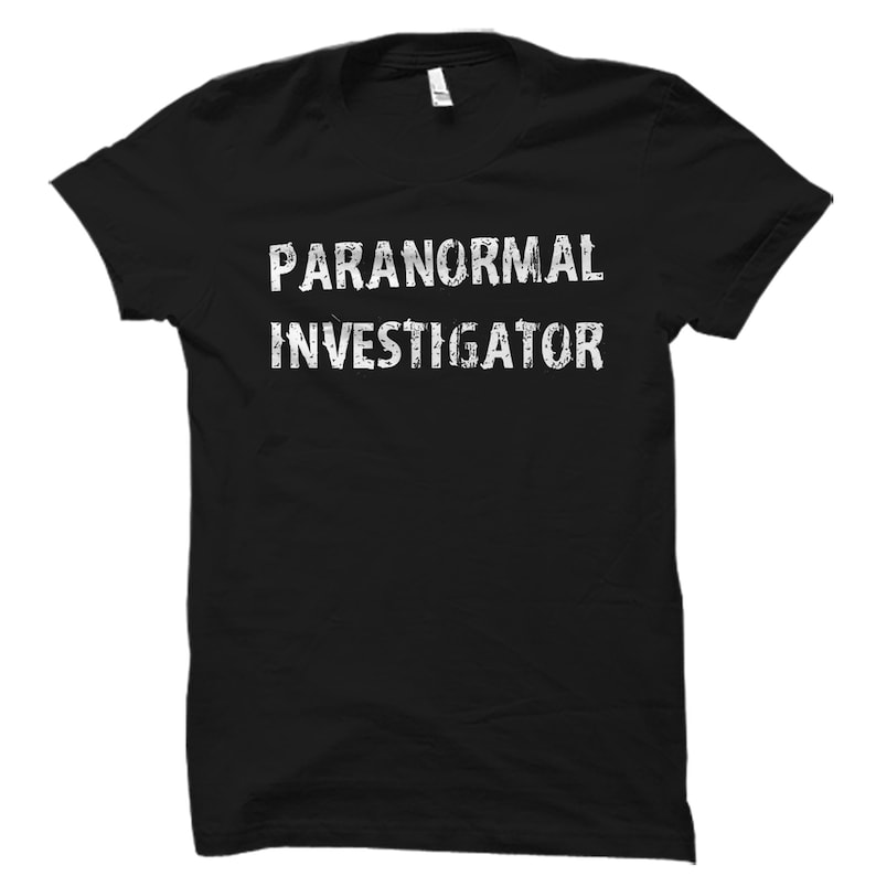 Puede incluir: Camiseta negra con texto blanco que dice "Paranormal Investigator".
