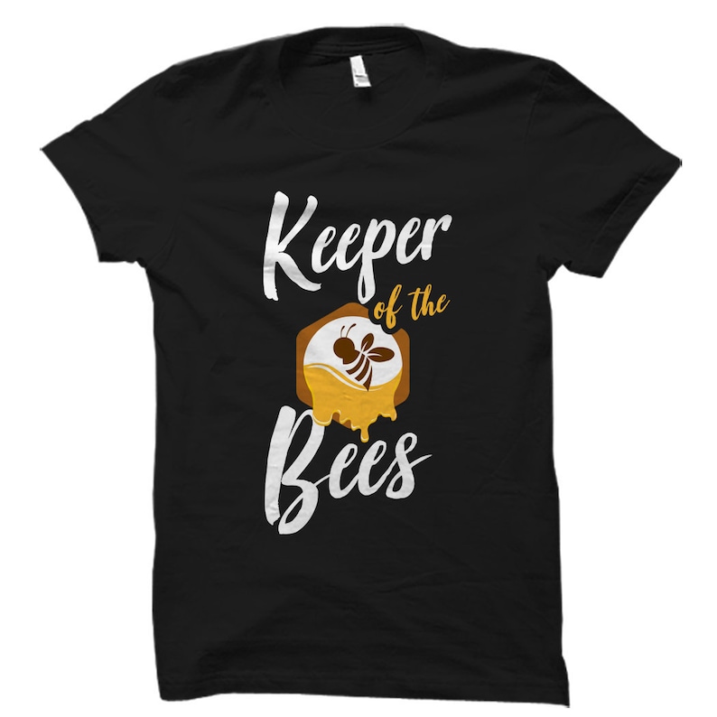 May include: Black t-shirt with white text that reads "Keeper of the Bees". A stylized image of a bee in a honeycomb is above the text.