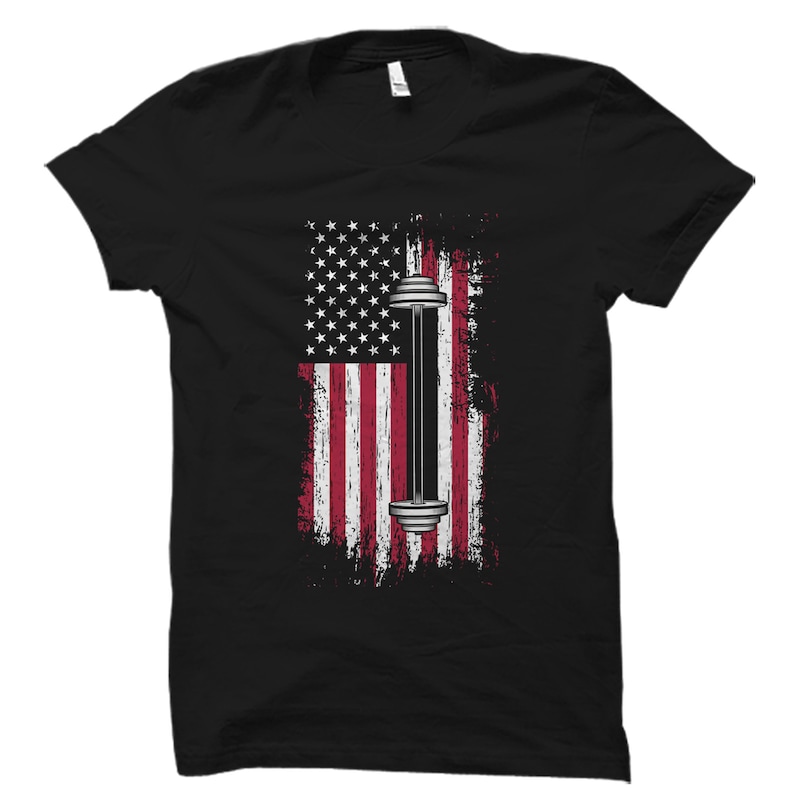 May include: Black t-shirt with a distressed American flag design featuring a barbell in the center.