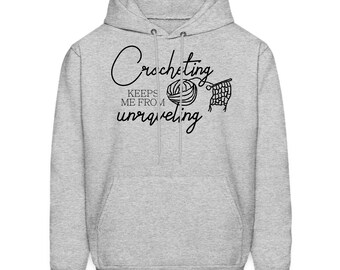 May include: Gray hooded sweatshirt with the text "Crocheting keeps me from unraveling" in black. The text is accompanied by a black illustration of a ball of yarn and a crochet hook.