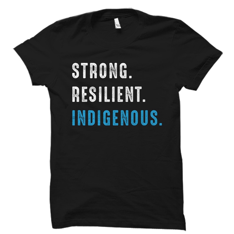 May include: Black t-shirt with white text that reads "STRONG. RESILIENT. INDIGENOUS." The text is in a distressed font style. The word "INDIGENOUS" is in blue.