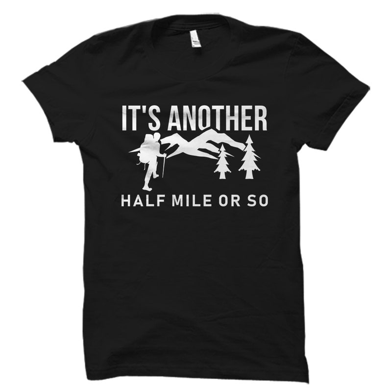 May include: Black t-shirt with a white graphic of a hiker with a backpack, mountains, and trees. The text "It's another half mile or so" is printed below the graphic.