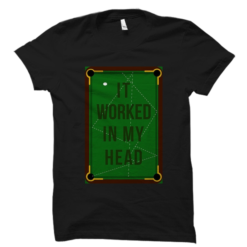 May include: Black t-shirt featuring a green pool table graphic with the text "IT WORKED IN MY HEAD". The pool table design includes a white cue ball and dotted lines. The shirt is a classic crew neck.