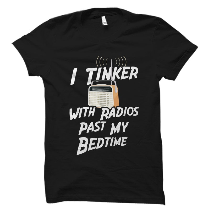 May include: Black t-shirt with white text that reads "I tinker with radios past my bedtime". A vintage radio is pictured above the text.