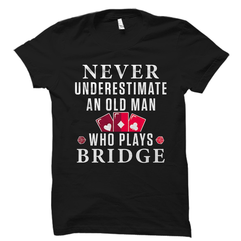 May include: Black t-shirt with white text that reads "Never underestimate an old man who plays bridge". The text is surrounded by a graphic of playing cards and dice.