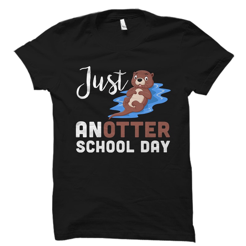 May include: Black t-shirt with a cartoon otter floating on its back in blue water. The text "Just another school day" is printed in white on the shirt.
