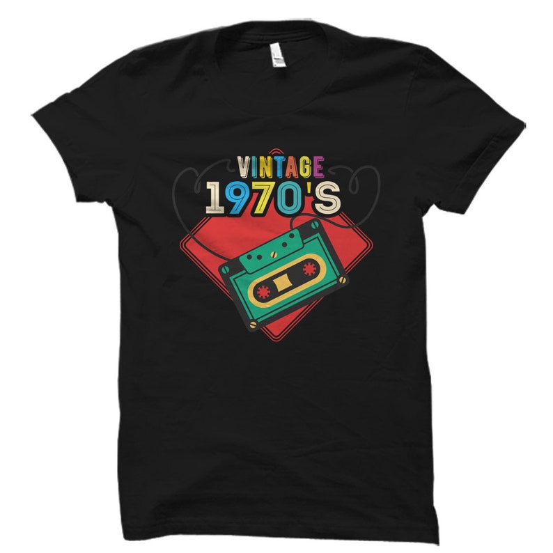 Może przedstawiać: Czarny T-shirt z vintage'owym wzorem z lat 70. z kasetą w kolorze czerwonym, ż&oacute;łtym, niebieskim, zielonym i r&oacute;żowym.